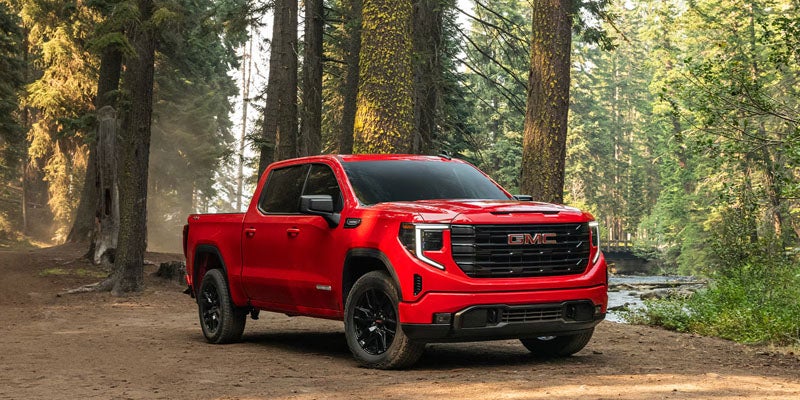 Red 2026 GMC Sierra 1500 Elevation parked on a forest trail