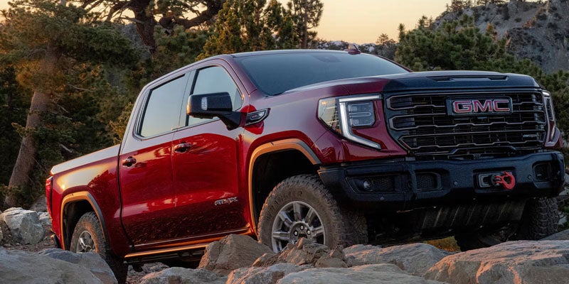 2026 GMC Sierra 1500 AT4X climbing a rocky trail at sunset