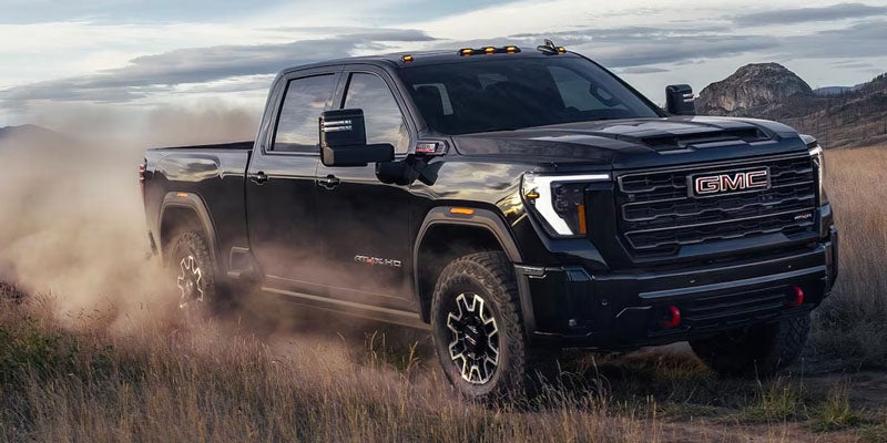 Black 2026 GMC Sierra HD AT4 powering across an open field