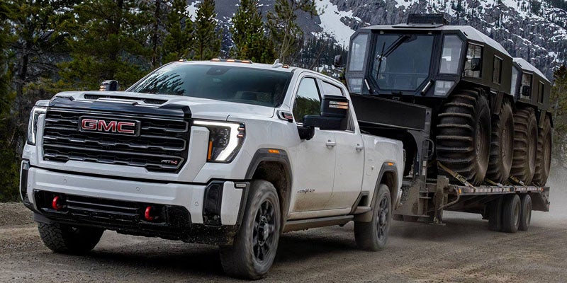 White 2026 GMC Sierra 3500 HD hauling equipment through the mountains